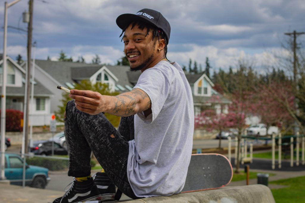 Skateboarder smiling and passing a joint