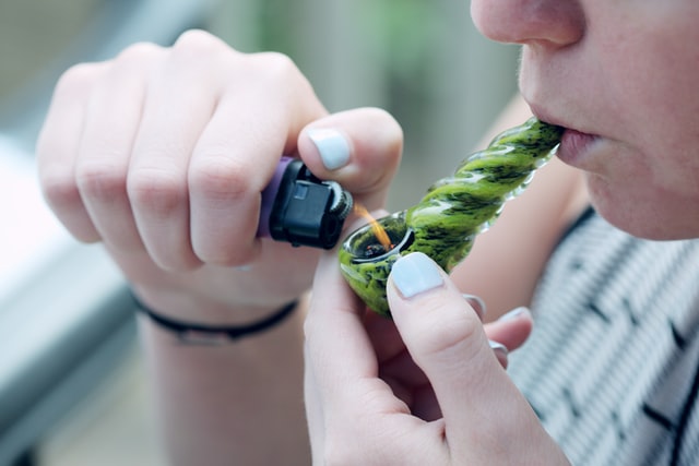 person-lighting-glass-weed-pipe