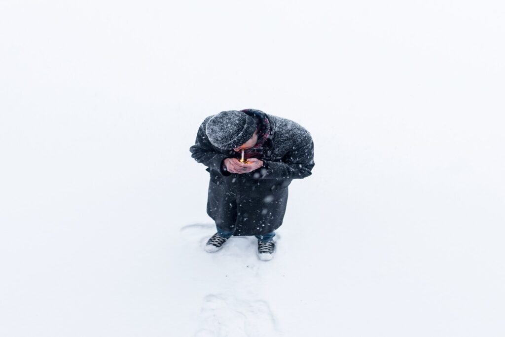 A man in the snow lighting a joint