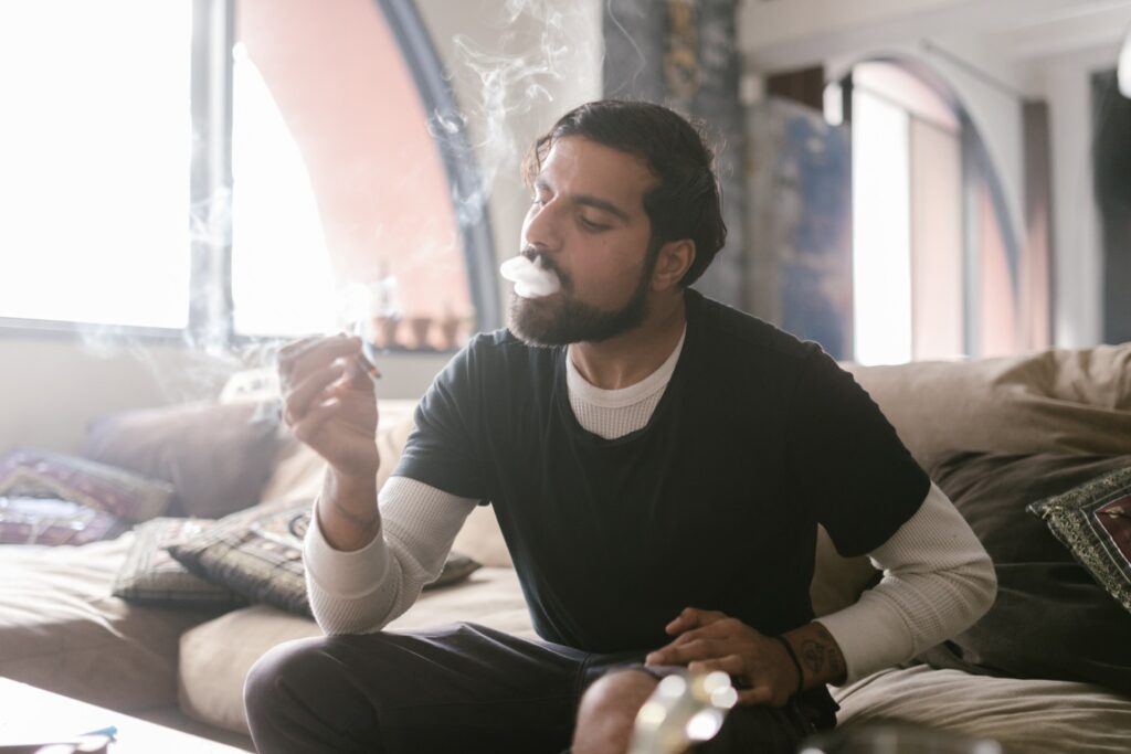 A man sitting on a couch and smoking weed