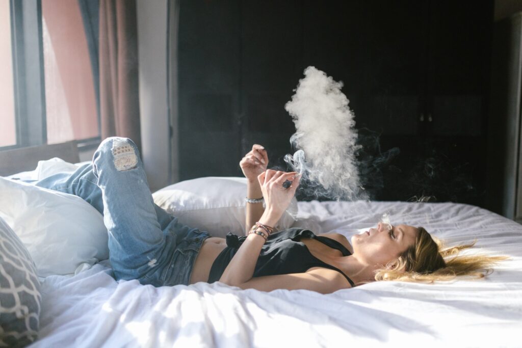 A woman lying on a bed and smoking weed