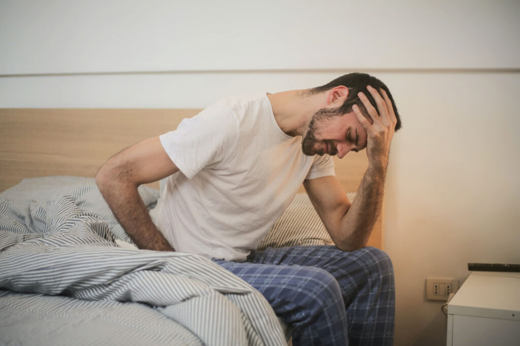 A man sick in bed holding his head